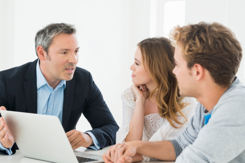 Consultor a explicar informação no portátil a um casal atento durante uma reunião